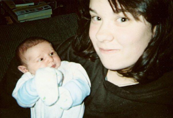 teenageer holding a newborn baby and smiling