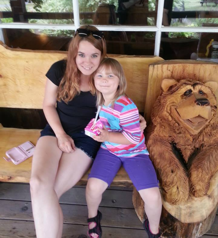 woman and a child sitting on a wooden bench outside a cafe