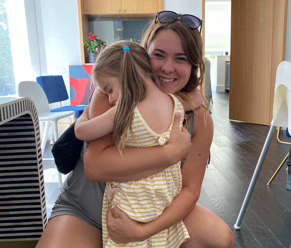 Woman smiling and hugging a small child in her living room