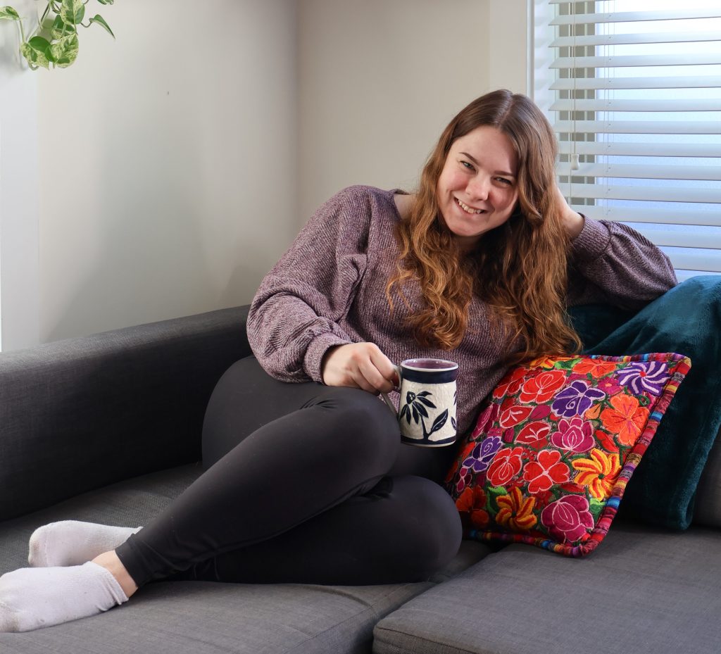Woma holding a coffee mug on her couch