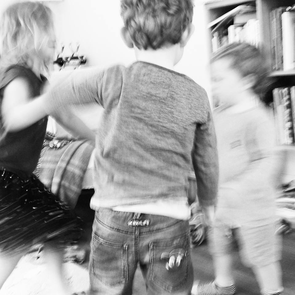 blurry photo of three young children holding hands and dancing 