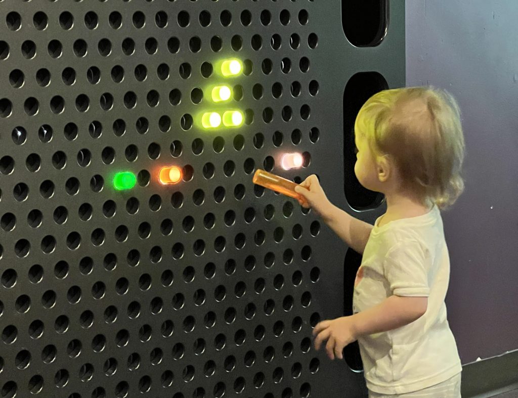 child putting a light peg into a big light board