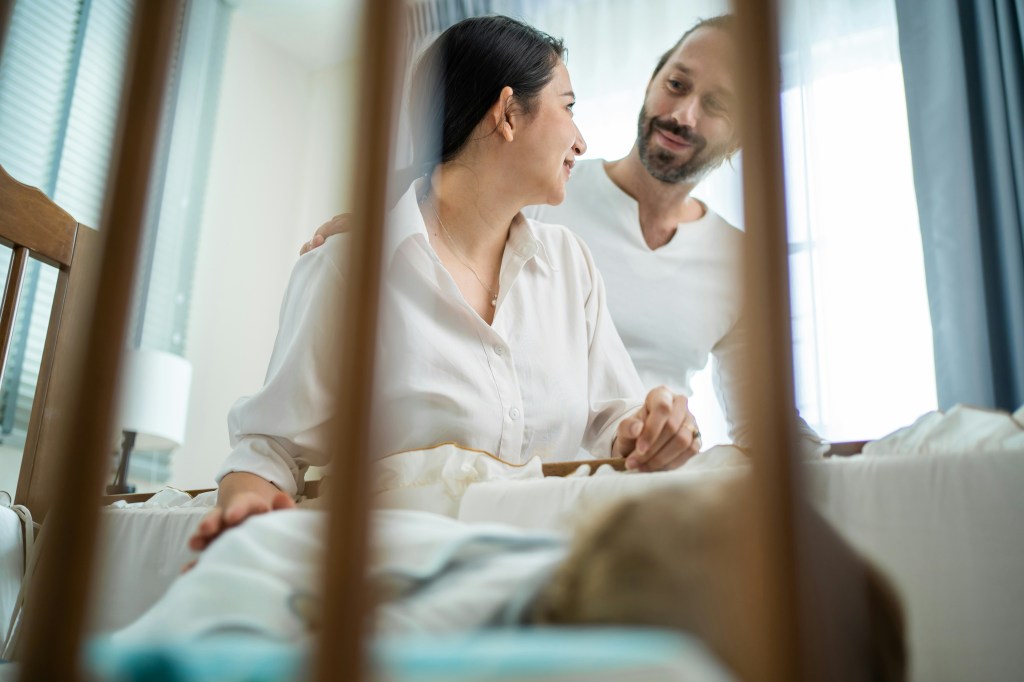 parents admiring their newborn baby in the crib.