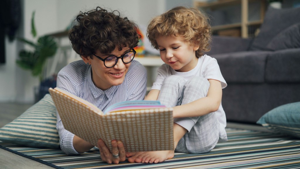 Parent reading to their older child on the floor